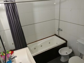 A bathroom with a bathtub, a sink, a bidet, and a toilet.