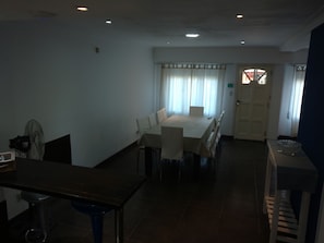 A dining area with a table and chairs, a fan, and a staircase leading to another room.