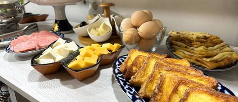 A breakfast buffet with various food items including eggs, cheese, ham, and French toast.