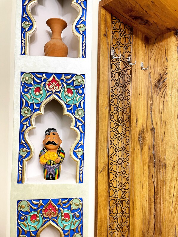 A wooden door with intricate geometric patterns and a decorative figure holding a bowl. - Bobosh Hotel (Bukhara)