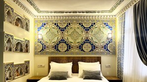 Une chambre d’hôtel avec un grand lit, des décorations murales élaborées et une couvre-lit à motifs.
