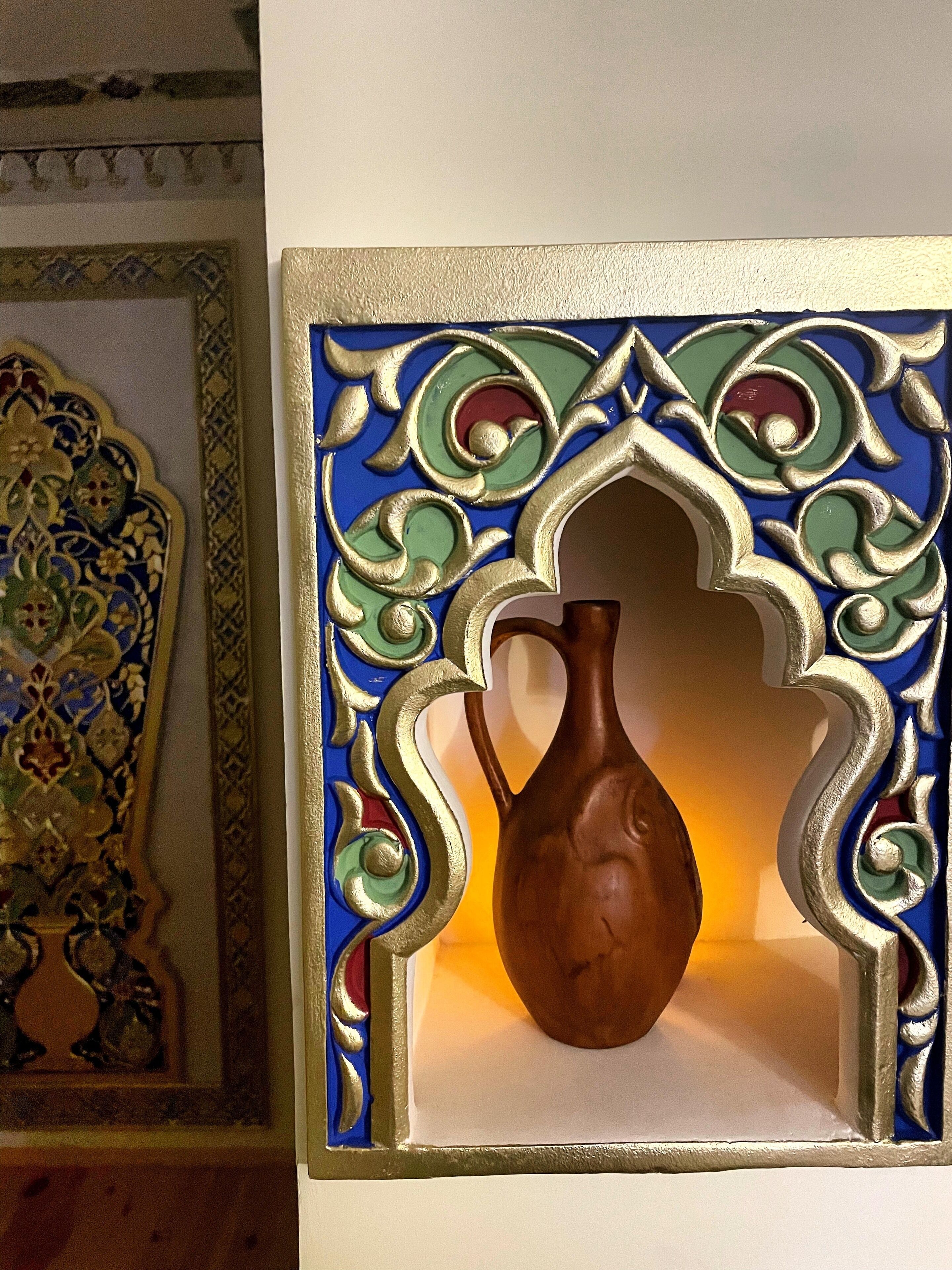 A decorative wall panel with a ceramic jug.
