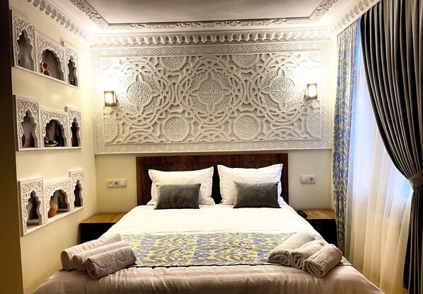 Un dormitorio con una cama grande, paneles decorativos en la pared y una colcha estampada.