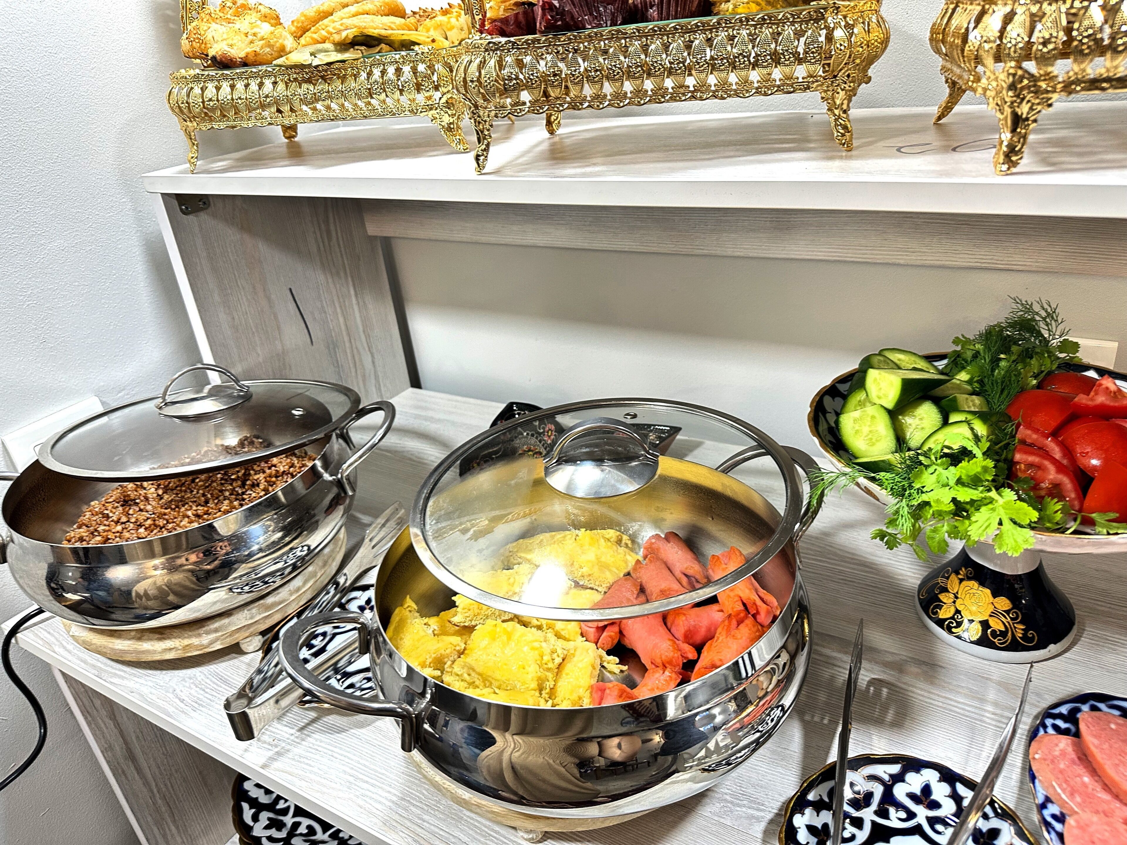 Una encimera de cocina con diversos alimentos y utensilios de cocina, incluyendo una olla con comida amarilla, un tazón de comida roja y un tazón de verduras.
