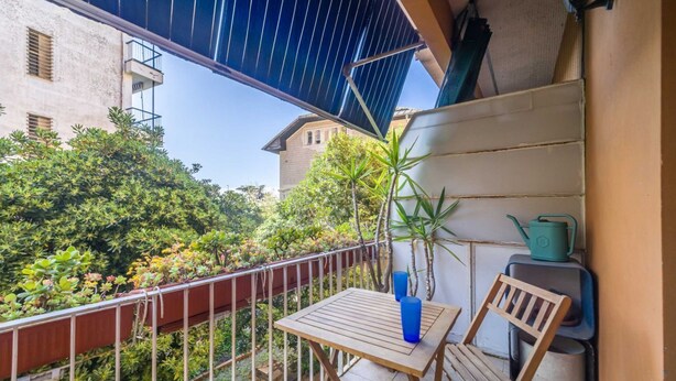 A balcony with a table and chair, a potted plant, and a blue vase. - GuestHost - Cozy apartment is located in a strategic position to visit the renowned Ligurian Riviera, suitable for families or groups of friends. Convenient for visiting the nearby towns of the Gulf of Tigullio, such as Chiavari, Santa Margherita and Por (Lavagna)