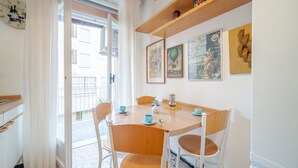 A dining area with a wooden table and chairs, a clock, and artwork on the walls. - GuestHost - Cozy apartment is located in a strategic position to visit the renowned Ligurian Riviera, suitable for families or groups of friends. Convenient for visiting the nearby towns of the Gulf of Tigullio, such as Chiavari, Santa Margherita and Por (Lavagna)