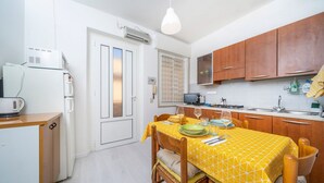 Cocina compacta con una mesa para dos, refrigerador, microondas y armarios de madera.