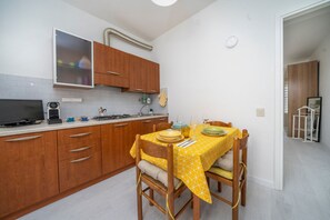 A compact kitchen with wooden cabinets, a dining table with yellow tablecloth, and a built-in stove.