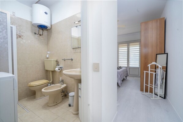 Un baño con inodoro, bidé, lavabo y espejo.