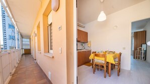 Un pasillo con piso de baldosas, un comedor con mesa y sillas, y una cocina con armarios de madera.