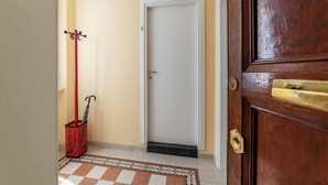 A hallway with a closed door, a red mop, and a patterned rug.