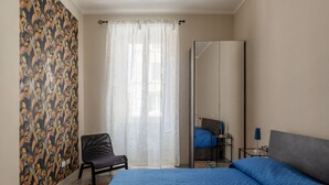 A bedroom with a bed, a chair, a wardrobe, and a mirror.