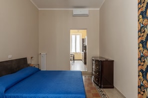 A bedroom with a bed, dresser, radiator, and an air conditioning unit.