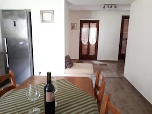A dining area with a table set for two, a bottle of wine, and two wine glasses.
