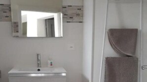 Casa de banho com lavatório branco, espelho e porta-toalhas.