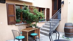 Un pequeño patio al aire libre con una mesa y sillas de madera, una escalera y un barril.