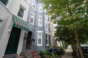 Stylish townhouses with green and white striped awnings and steps leading up to the entrance.