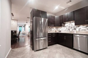 Enjoy cooking in this well-equipped kitchen with a dishwasher, refrigerator, and tiled backsplash.