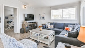 Ein modernes Wohnzimmer mit einem grauen Sofa, einem weißen Couchtisch und einem Fernseher.