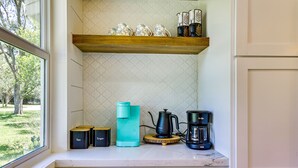 A kitchen with a coffee maker, sugar container, and tea container on the counter.