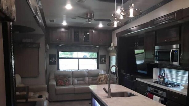 A compact RV kitchen with a central island, a microwave, and a stove. - Arthur's Dream (Hemphill)