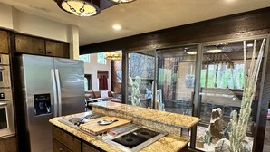 A kitchen with a built-in refrigerator, a stove, and a water dispenser. - 1980s Rustic Ranch house is the Perfect Place for events at the Lazy E. (Guthrie)