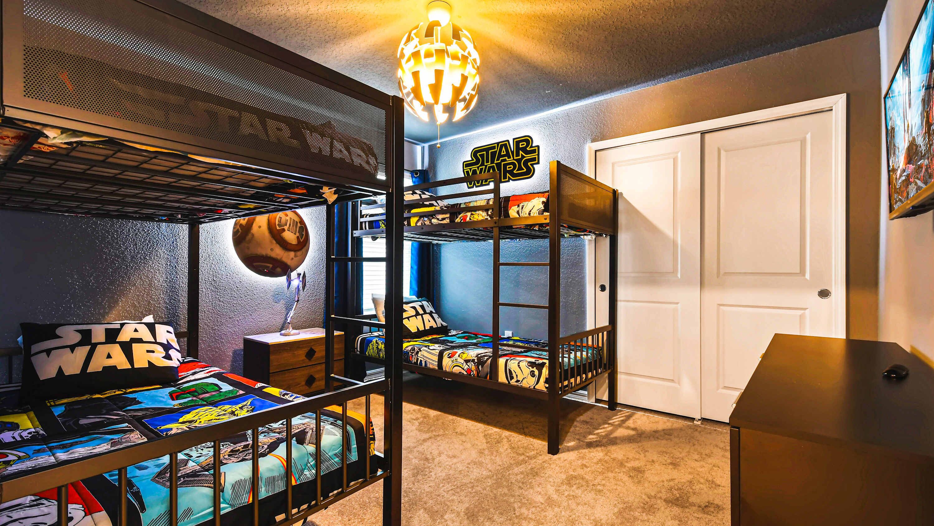 A Star Wars-themed bunk bed room with a Star Wars poster, a desk, and a Star Wars lamp.