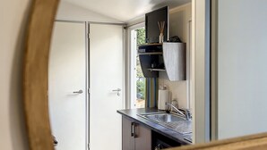 Une cuisine moderne dotée d’un four encastré, d’un évier et d’une fenêtre donnant sur un jardin.