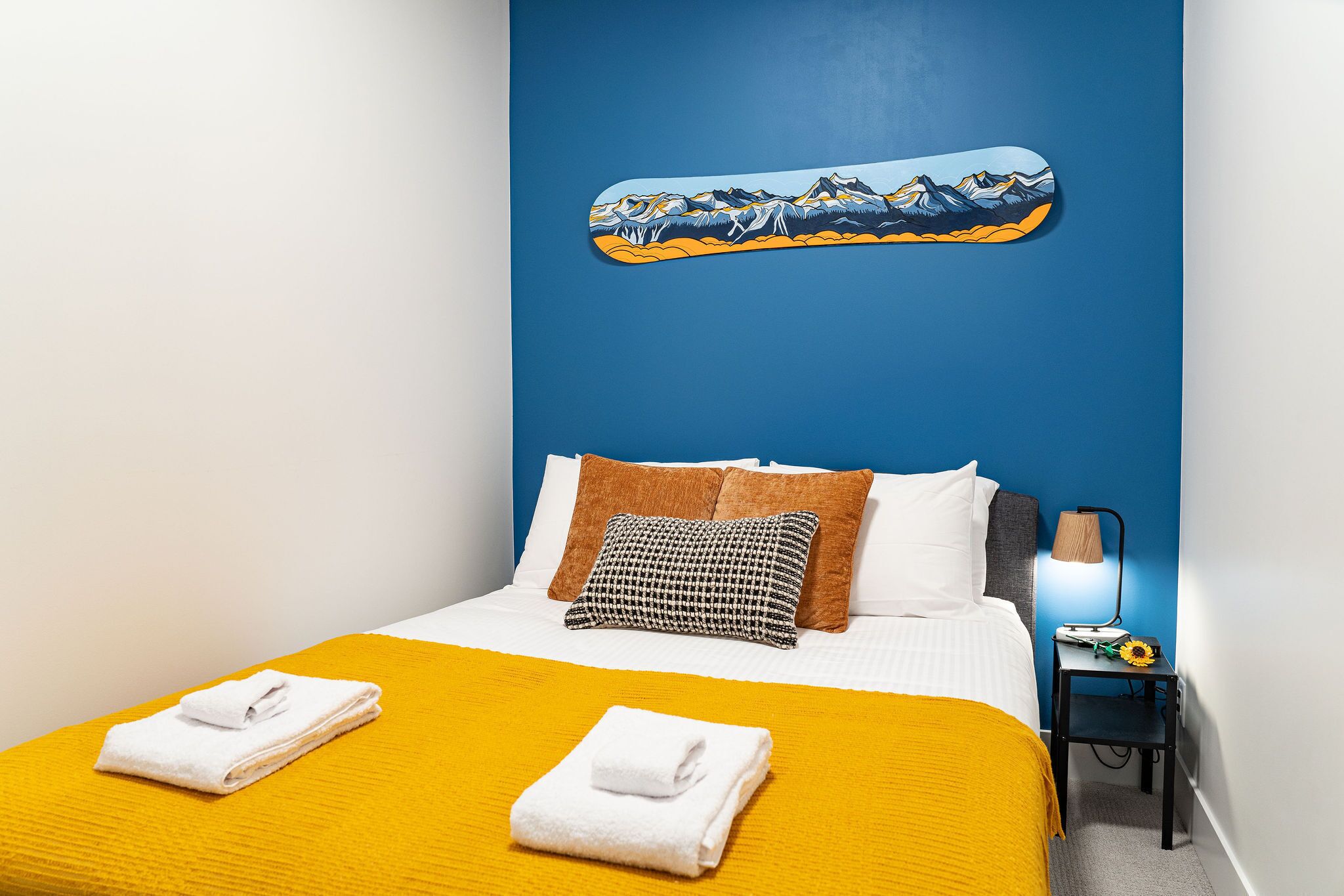 Ein Hotelzimmer mit einem Bett, einem Nachttisch, einer Lampe und einem Bild an der Wand.
