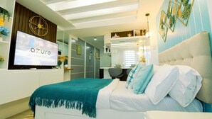 A modern bedroom with a bed, a TV displaying 'The Azure Experience', a mirror, and a desk with a chair.