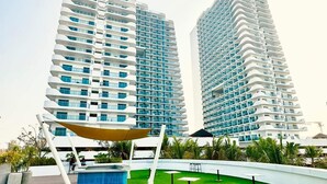 A modern hotel with a rooftop garden, featuring a pool and outdoor seating.