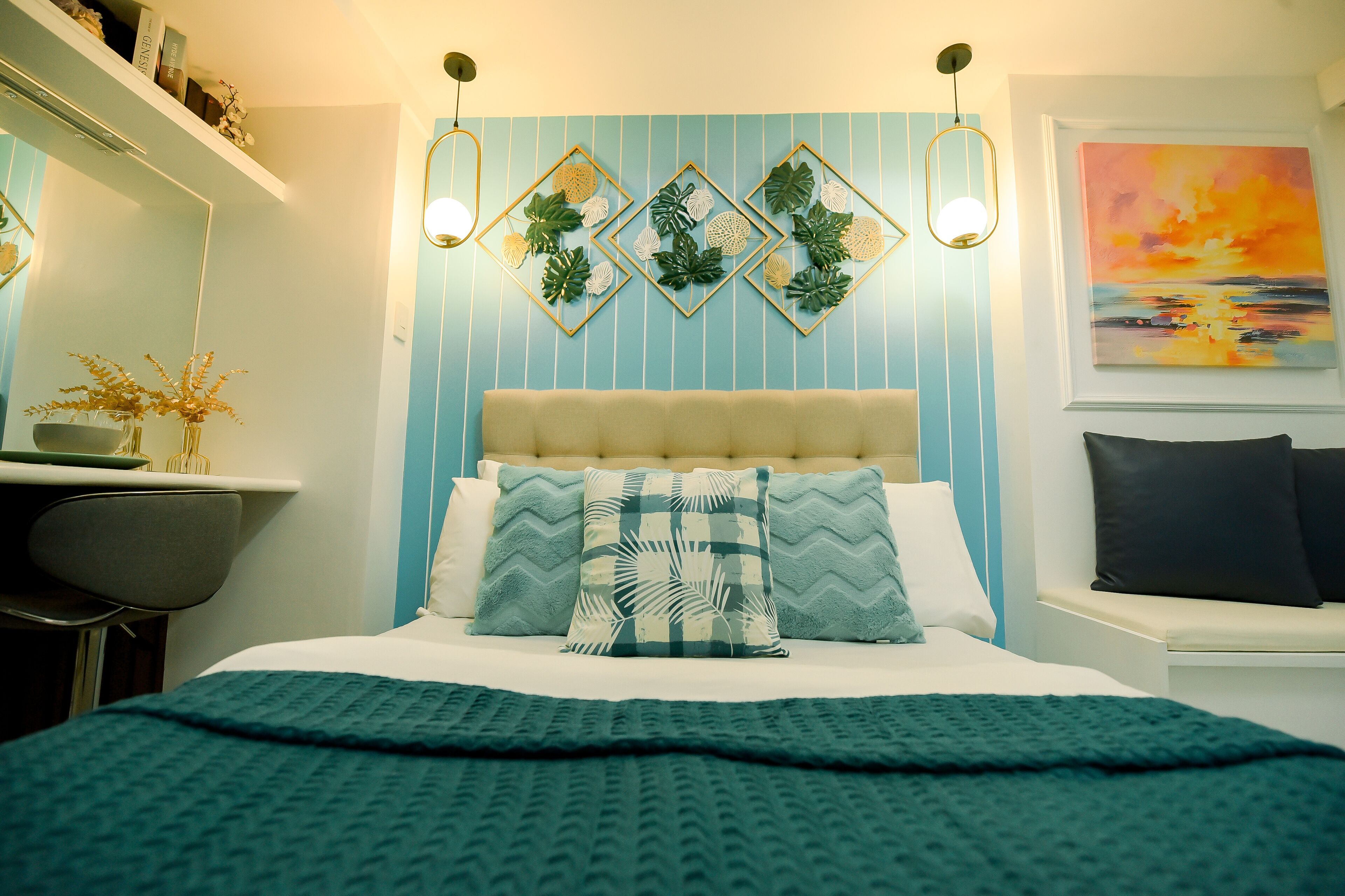 Quarto com cama, escrivaninha, cadeira, prateleira na parede e um quadro.