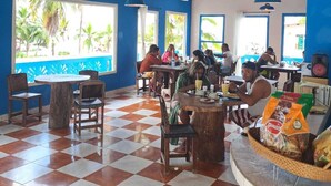A restaurant with a checkered floor, blue walls, and large windows with views of palm trees. - Villa Bella Portobelo (Portobelo)