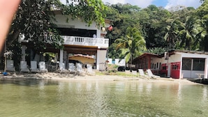A beachfront property with a pool, lounge chairs, and a building with a balcony. - Villa Bella Portobelo (Portobelo)