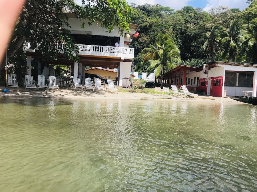 Una propietat a peu de platja amb piscina, gandules i un edifici amb balcó.