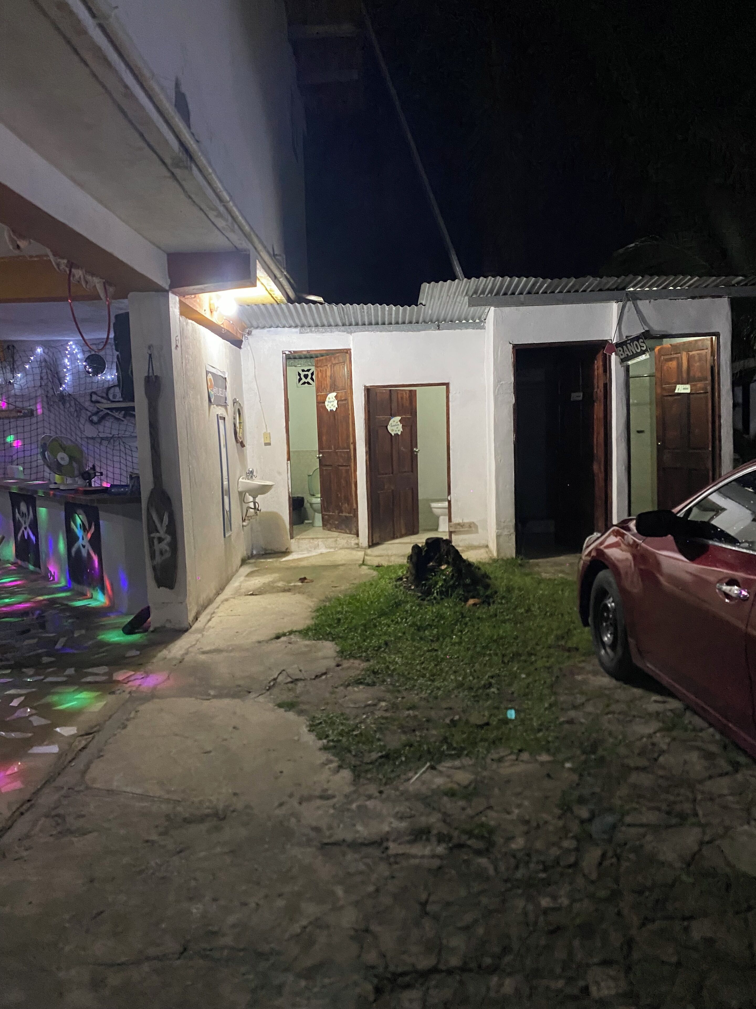 Un petit bâtiment blanc, doté de deux portes en bois, avec une voiture garée devant.