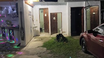 Un petit bâtiment blanc, doté de deux portes en bois, avec une voiture garée devant.