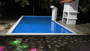 An outdoor swimming pool with a tiled deck and a small white structure with a red roof. - Villa Bella Portobelo (Portobelo)