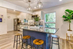 Enjoy cooking in this well-equipped kitchen with a large island, stainless steel appliances, and a geometric-patterned backsplash.