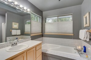 Une salle de bain avec deux lavabos, un grand miroir et une fenêtre avec des stores.