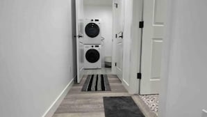 Un couloir étroit, dont le sol est orné de motifs, mène à une pièce où sont installées deux machines à laver superposées.