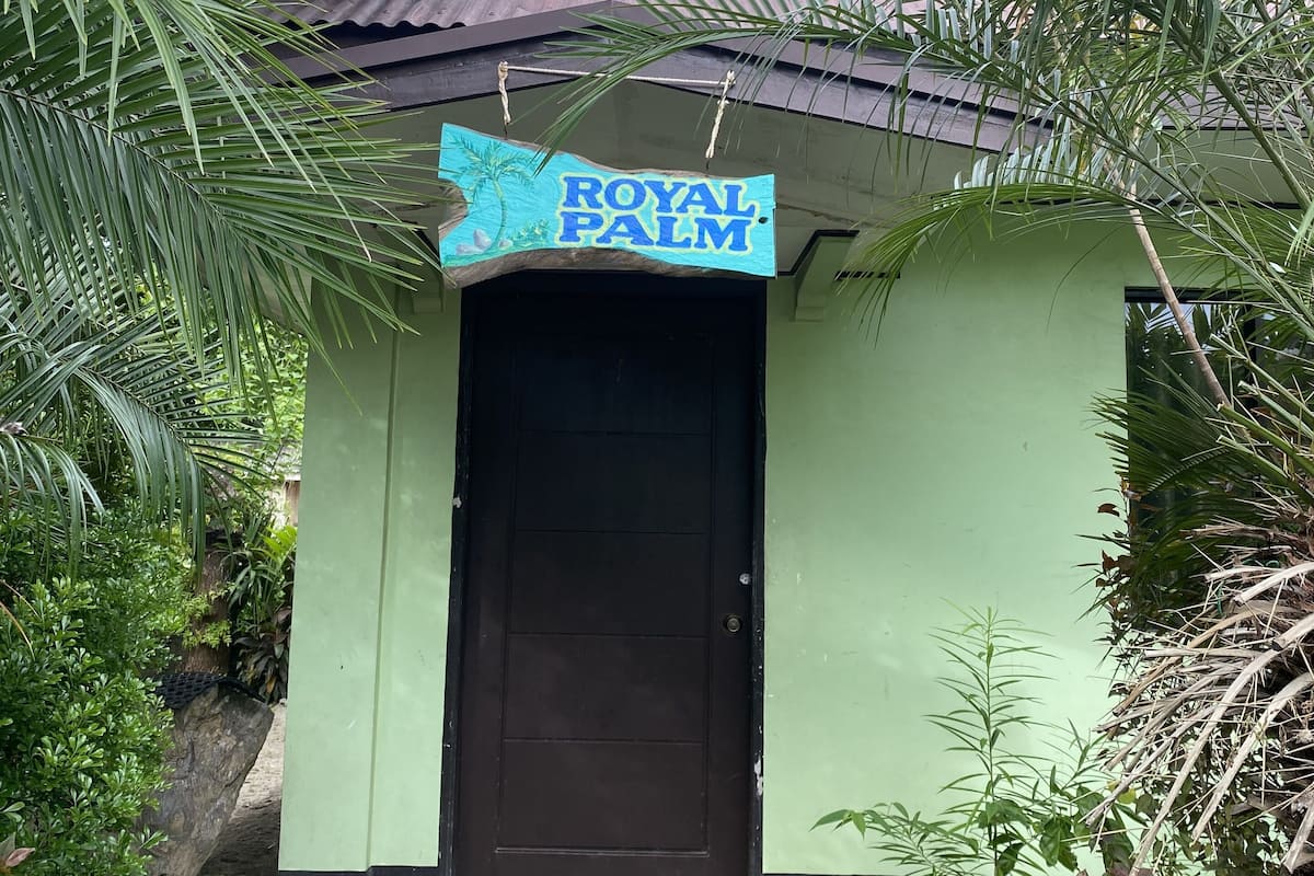 A building with a sign reading "ROYAL PALM" and a brown door.
