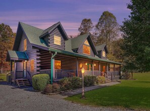Eine Blockhütte mit Veranda, mehreren Fenstern und einem gepflegten Rasen.