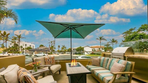 Een terras met tuinmeubilair, een vuurkuil en een barbecue.