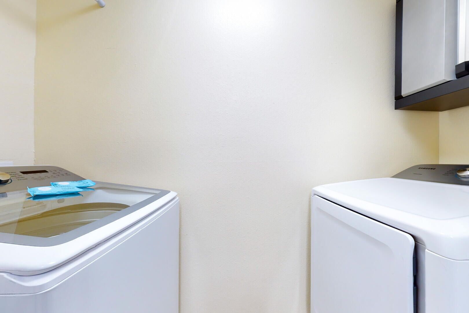 A laundry area with a washing machine and dryer, a control panel, and a wall-mounted mirror.
