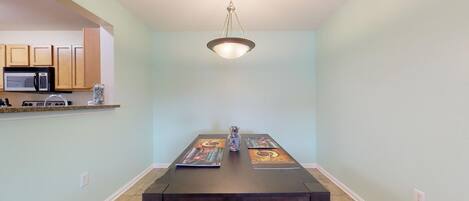 A dining area with a dark wooden table, light blue walls, and a hanging light fixture.