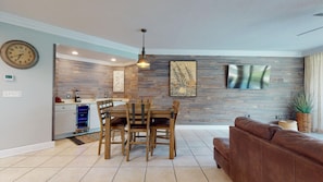 A modern kitchen with a dining area, a large clock, and a flat-screen TV. - 3br/3ba w/ Lazy River & Slide Sleeps 8 (Orange Beach)