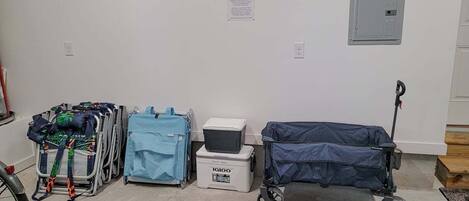 A wheelchair, a blue suitcase, and a storage box in a room with white walls and a door.