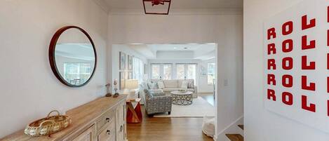 A hallway with a wooden cabinet, a round mirror, and a wall with red text.