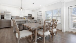 A modern kitchen with white cabinets, stainless steel appliances, and a wooden dining table with chairs. - Hidden Gem! 3br/2.5ba Home/pool/near Beach/slps 10 (Orange Beach)